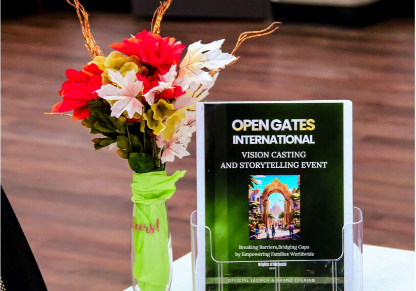 A display with brochures for an event and a vase of flowers